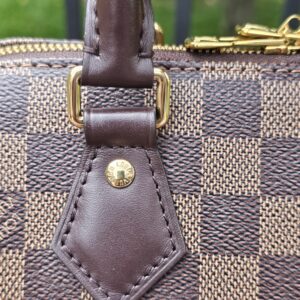 Handle attachment tab and gold-tone hardware on the Speedy Bandouliere 20