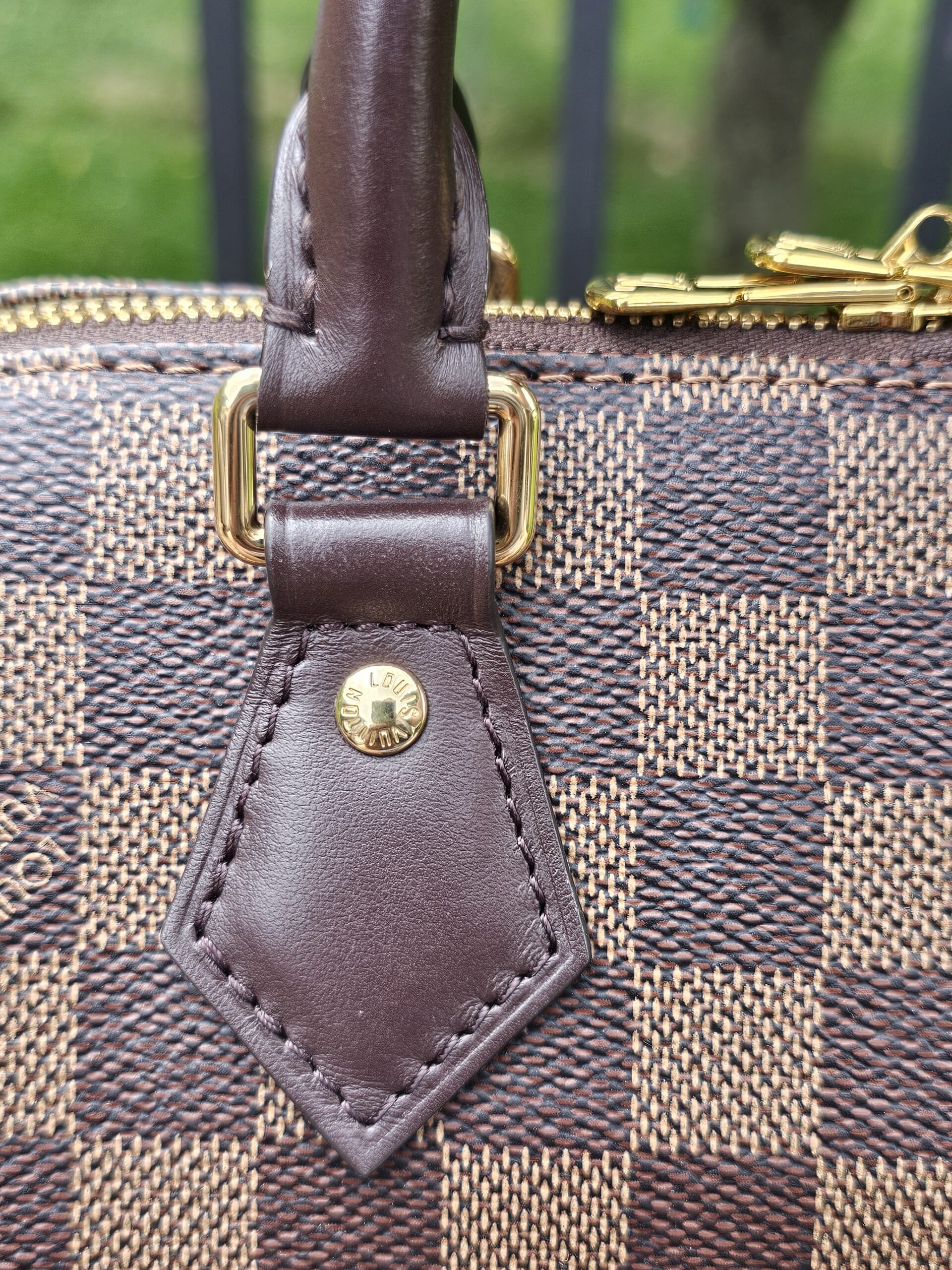 Handle attachment tab and gold-tone hardware on the Speedy Bandouliere 20