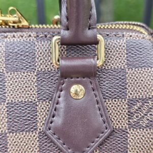 Close-up of the leather handle tab and stud on the Speedy Bandouliere 20