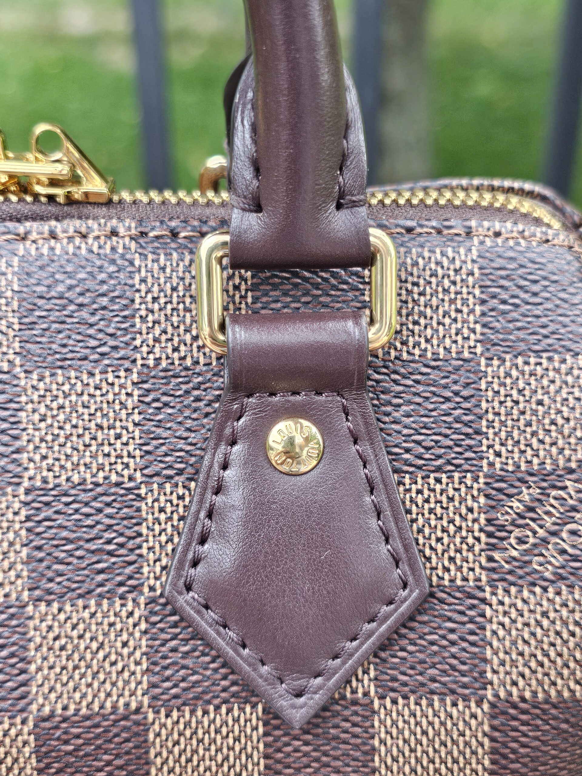 Close-up of the leather handle tab and stud on the Speedy Bandouliere 20