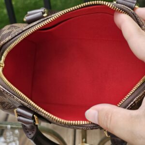 Speedy Bandouliere 20 held open to show the red fabric interior