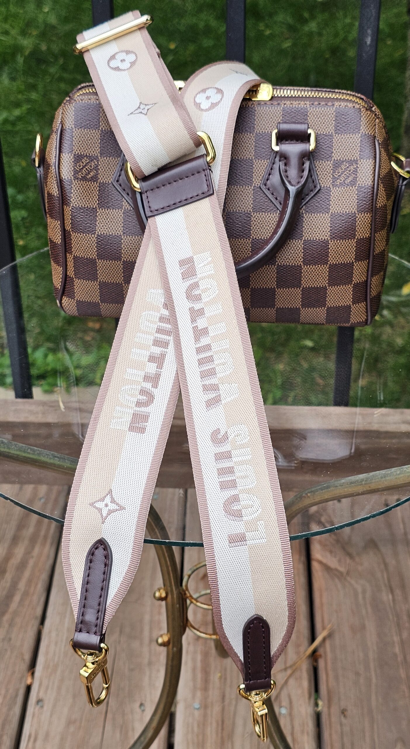 Damier Ebene Speedy Bandouliere 20 laid out with its beige monogram jacquard shoulder strap