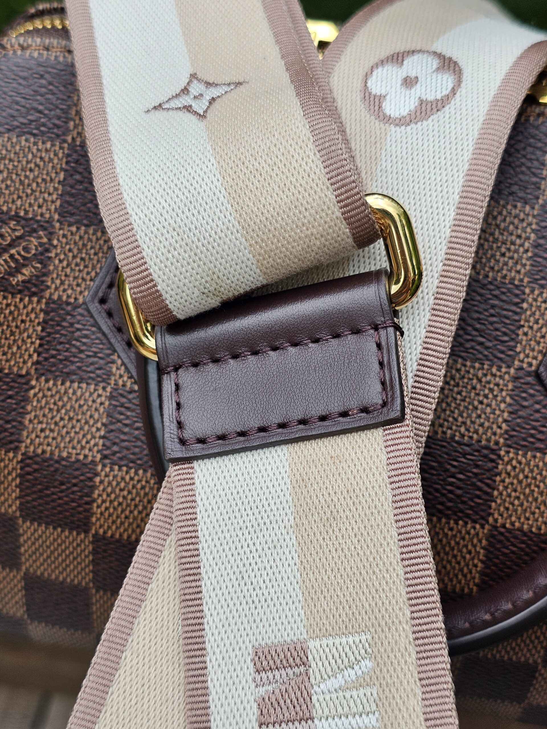 Close-up of the beige monogram jacquard shoulder strap against the Damier Ebene canvas