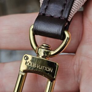 Close-up of an engraved gold-tone snap hook on the Louis Vuitton jacquard shoulder strap
