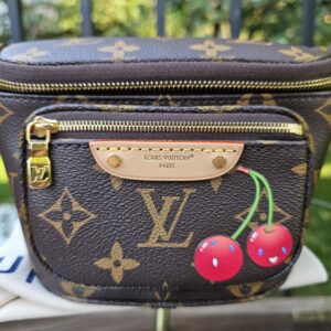 Front view of the Monogram Cerises Mini Bumbag showing the smiling cherry motif and leather name tag