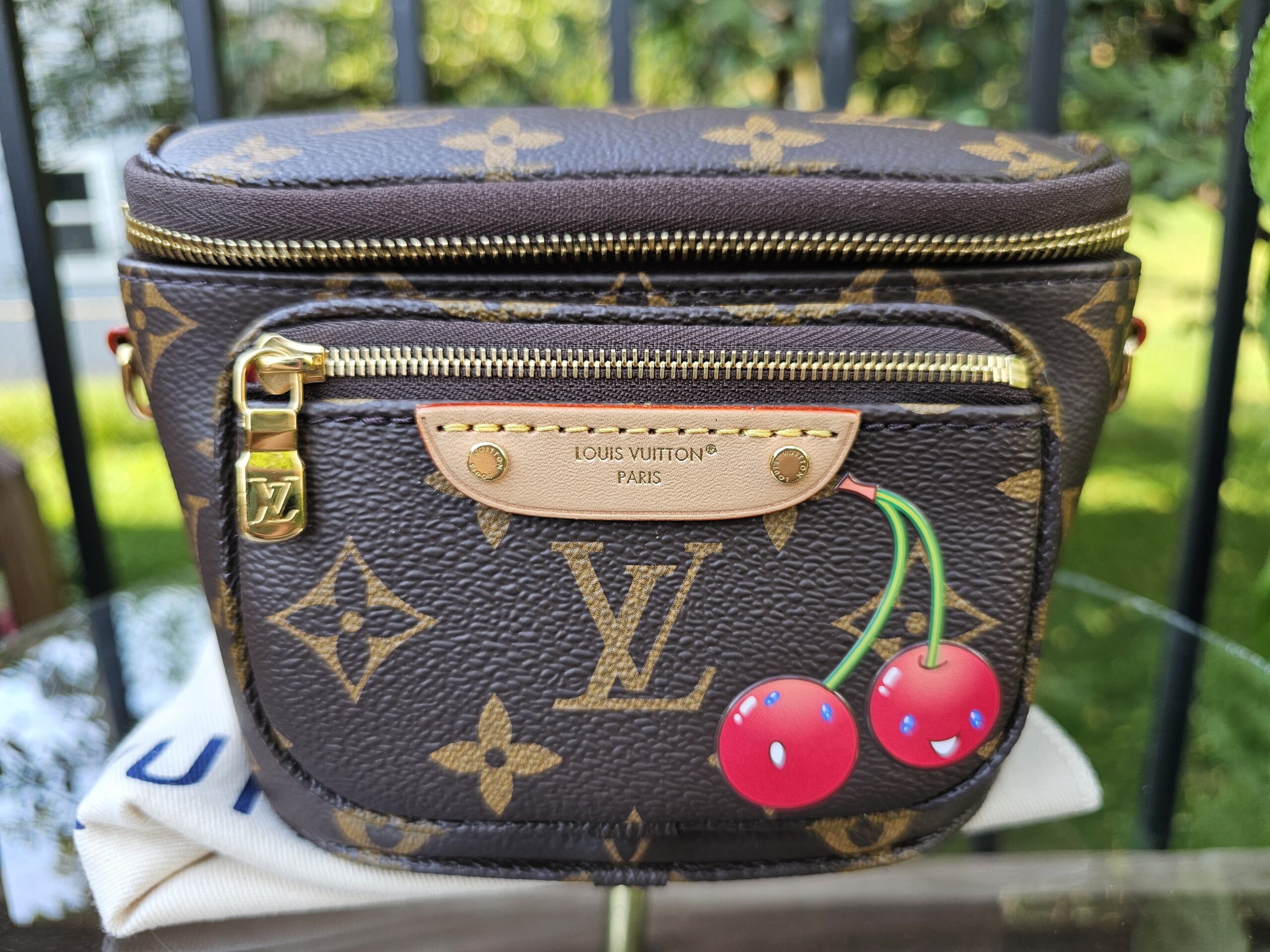 Front view of the Monogram Cerises Mini Bumbag showing the smiling cherry motif and leather name tag
