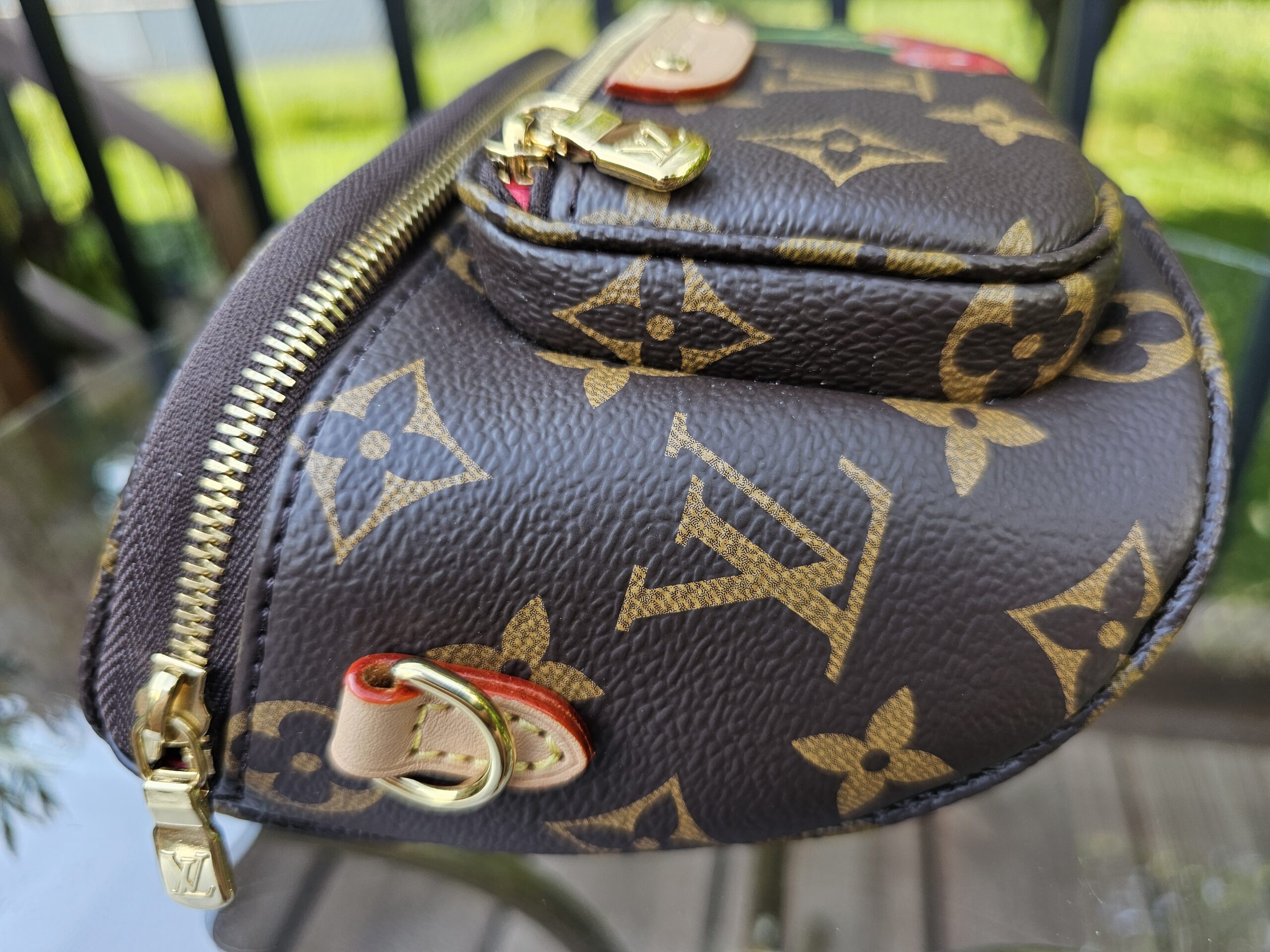 Angled view of the Monogram Cerises Mini Bumbag showing the zip top and gold-tone hardware