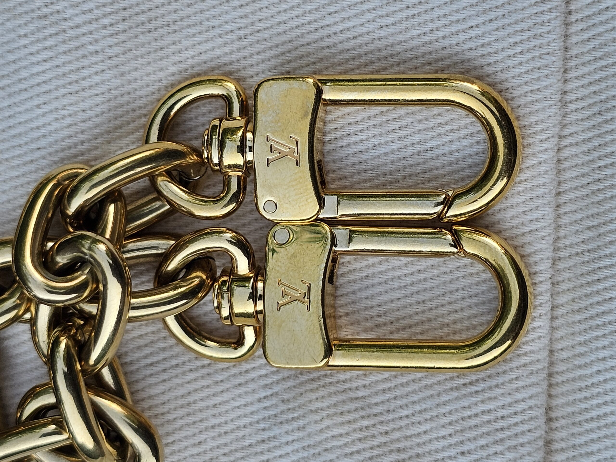 Engraved gold-tone LV clasps on the removable chain strap of the Cerises Mini Bumbag