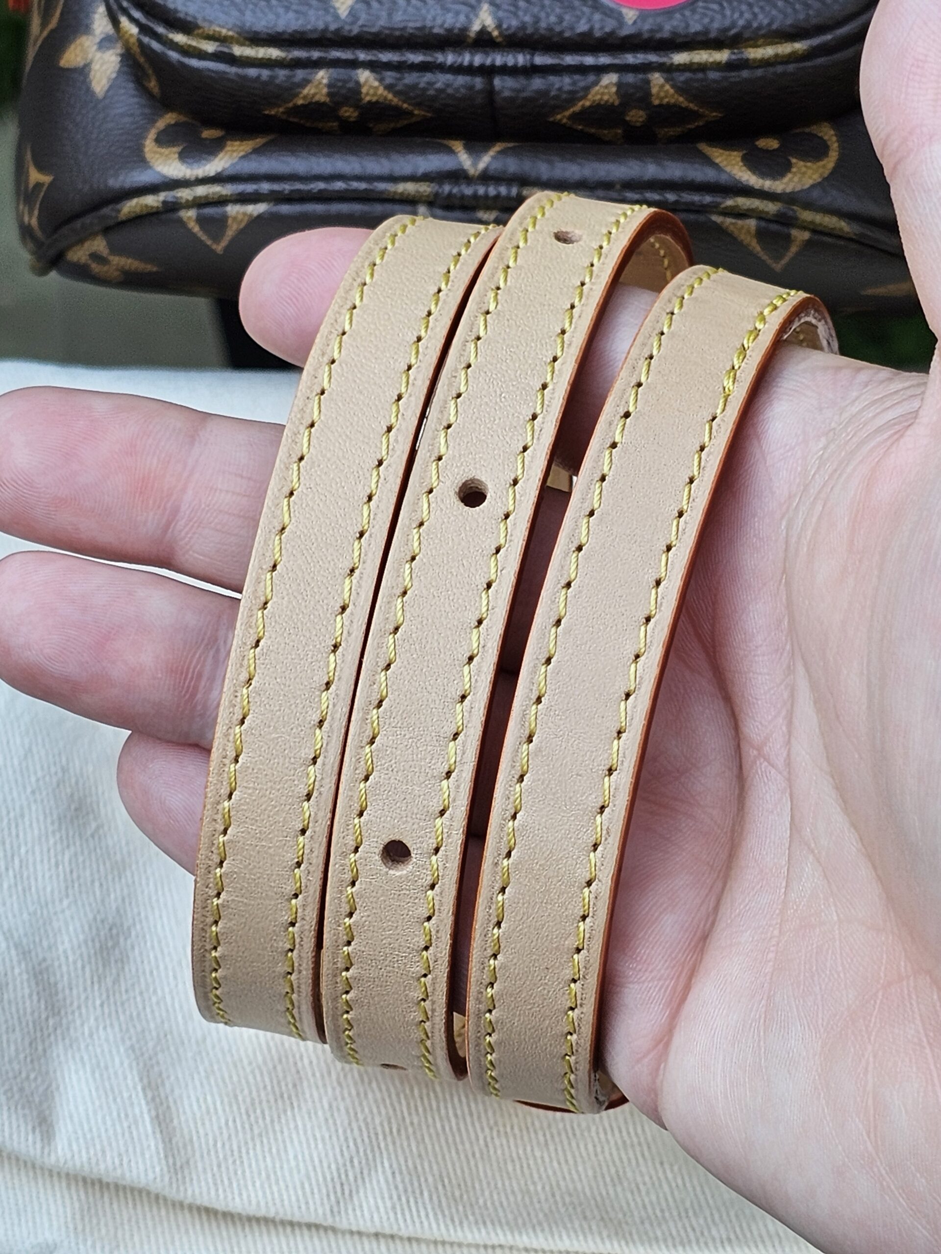 Adjustable vachetta leather strap for the Cerises Mini Bumbag held in hand