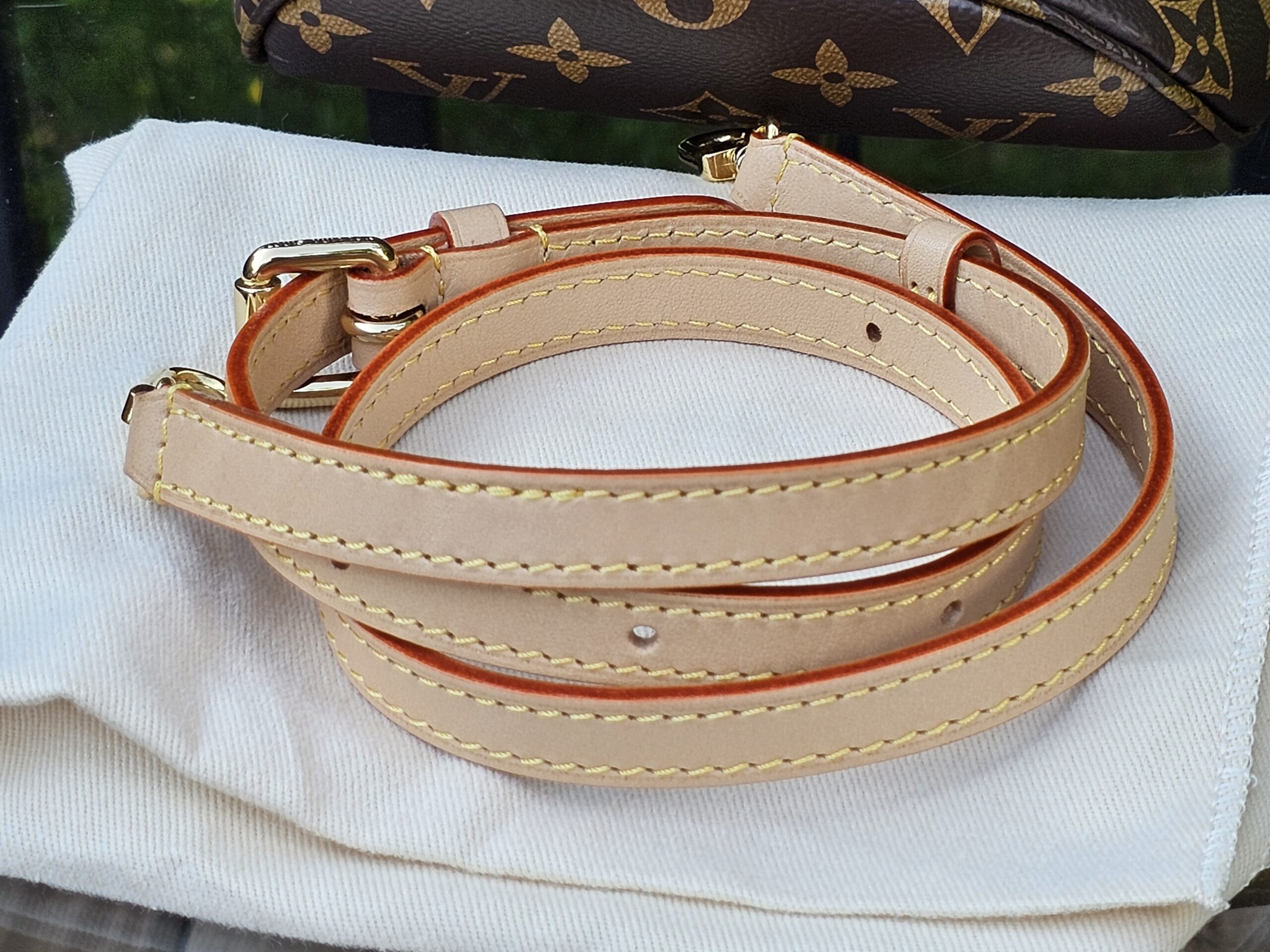 Vachetta leather strap for the Cerises Mini Bumbag coiled on its dust bag