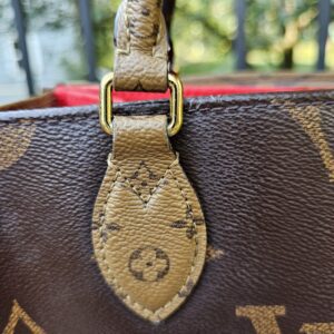 Handle attachment tab and gold-tone hardware on the Reverse Monogram Giant OnTheGo PM