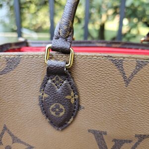 Close-up of a handle attachment on the OnTheGo PM with wear to the surrounding canvas