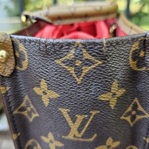 Side gusset of the OnTheGo PM opened to show the giant monogram canvas and gold-tone studs