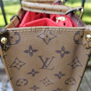 Opposite gusset of the Reverse Monogram Giant OnTheGo PM with the red interior visible
