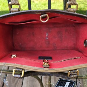 Reverse Monogram Giant OnTheGo PM held open to show the red textile interior and staining