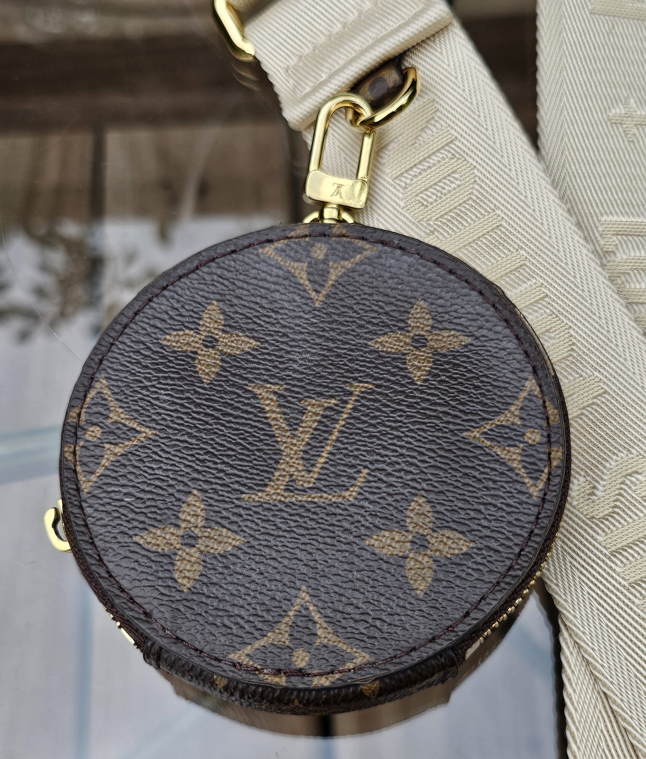 Front of the Monogram round pouch with its gold-tone snap hook