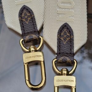 Both ends of the cream jacquard strap with Monogram tabs and snap hooks
