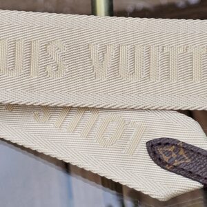 LOUIS VUITTON lettering woven into the cream jacquard strap
