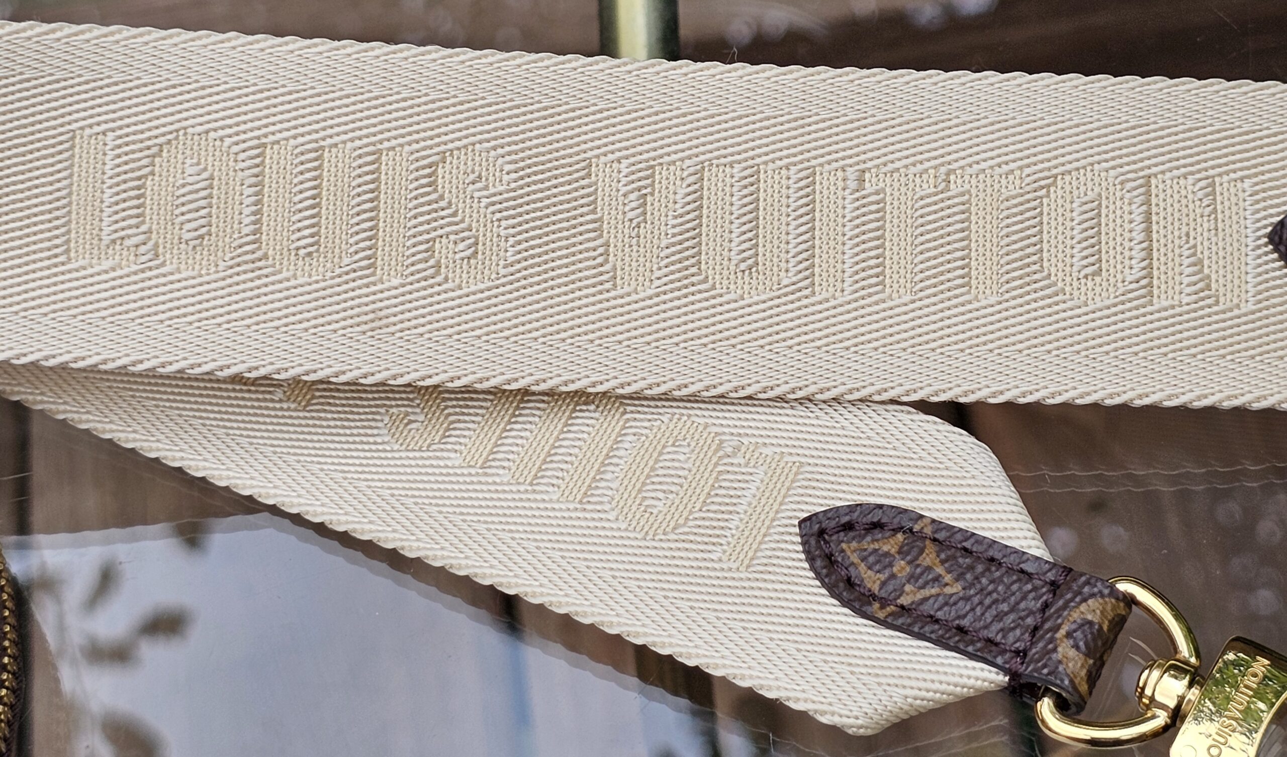 LOUIS VUITTON lettering woven into the cream jacquard strap