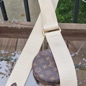 Cream jacquard adjustable strap laid out with the Monogram round pouch