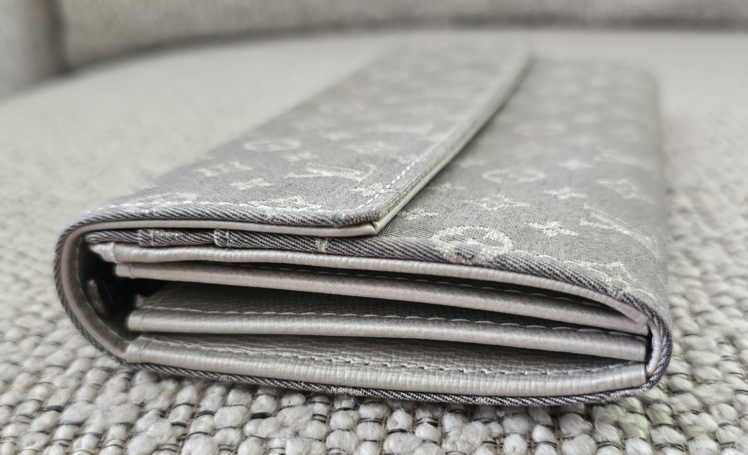 Side profile of the gray Monogram Mini Lin Sarah Wallet showing the folded card compartments
