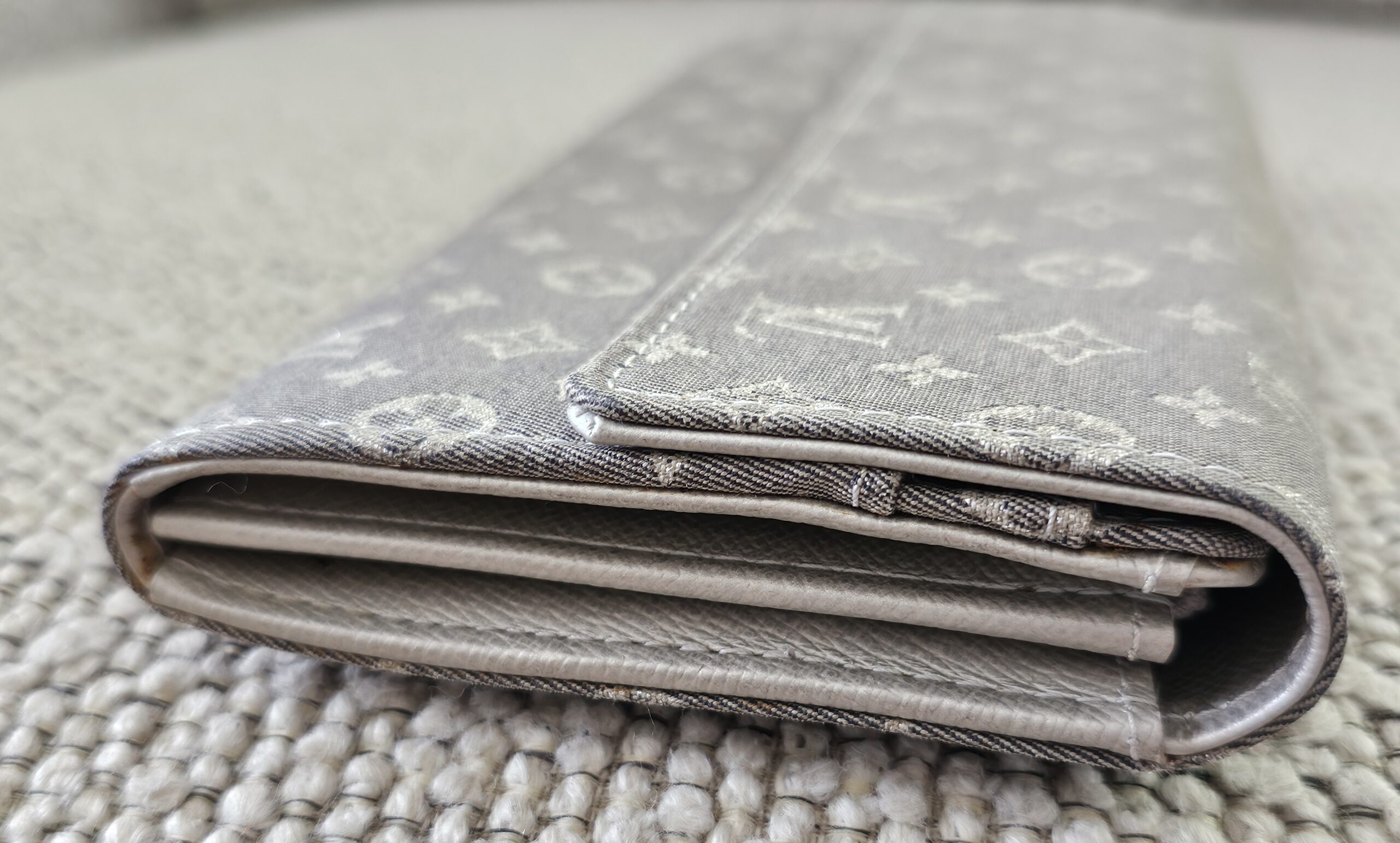 Edge view of the gray Mini Lin Sarah Wallet showing light corner and edge wear