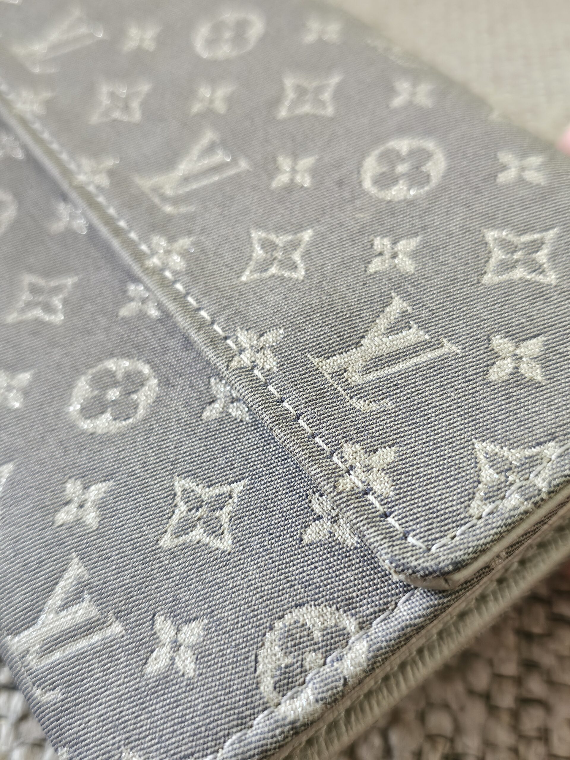 Close-up of the gray Monogram Mini Lin woven textile on the Sarah Wallet