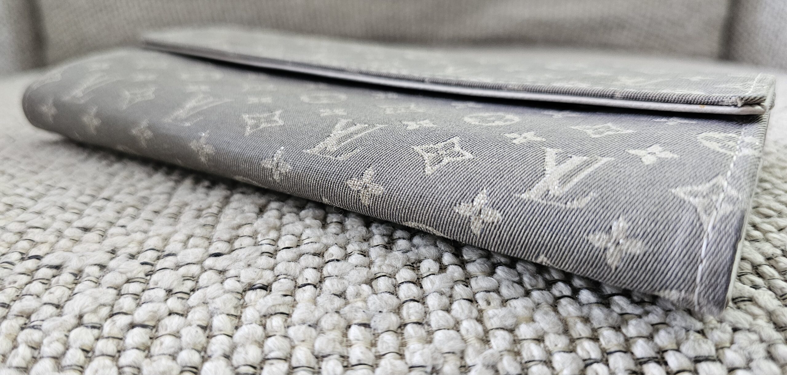 Closed profile of the gray Monogram Mini Lin Sarah Wallet showing the snap flap