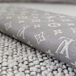 Flap of the gray Mini Lin Sarah Wallet showing the woven monogram pattern