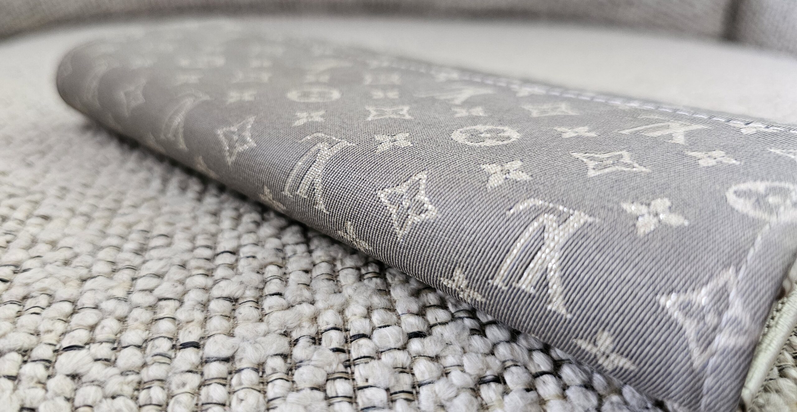 Flap of the gray Mini Lin Sarah Wallet showing the woven monogram pattern