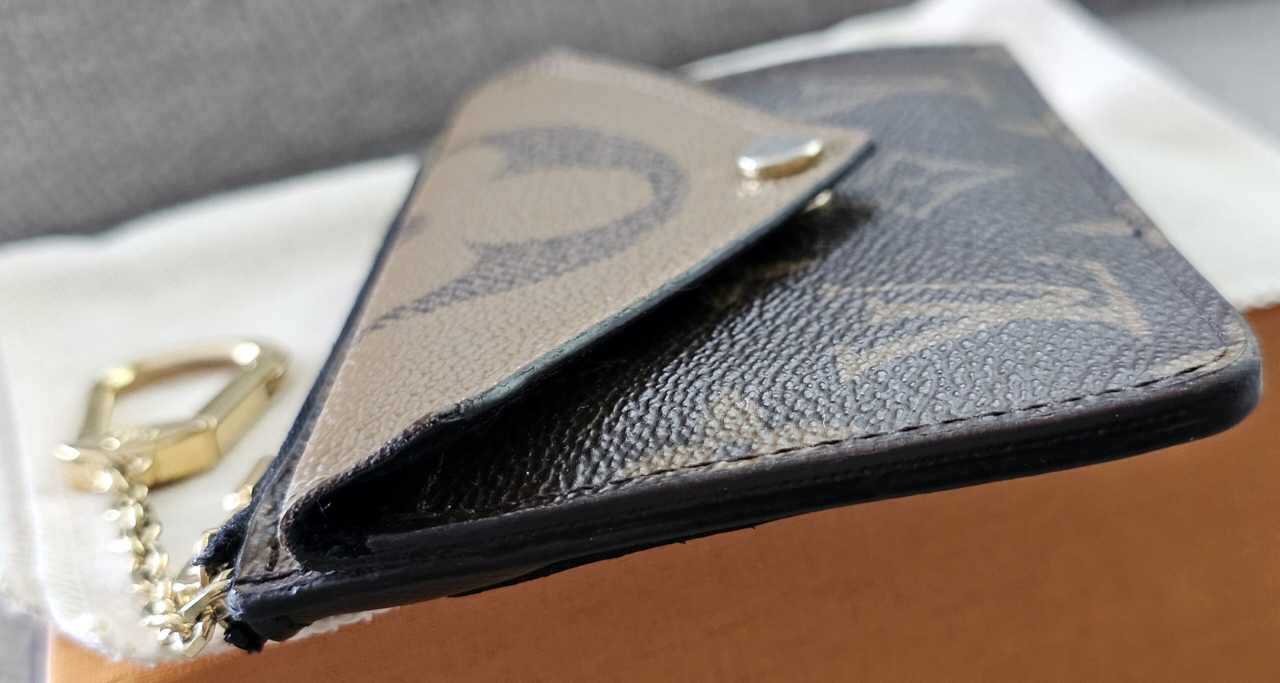 Angled view of the Monogram Reverse Recto Verso card holder with its dust bag