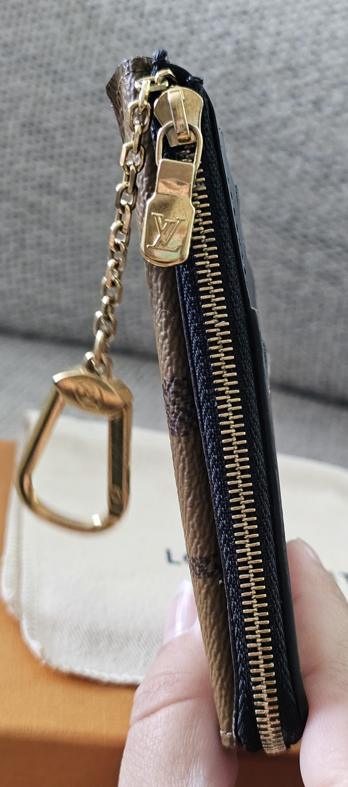 Reverse Monogram Recto Verso card holder held in hand showing its compact size and chain