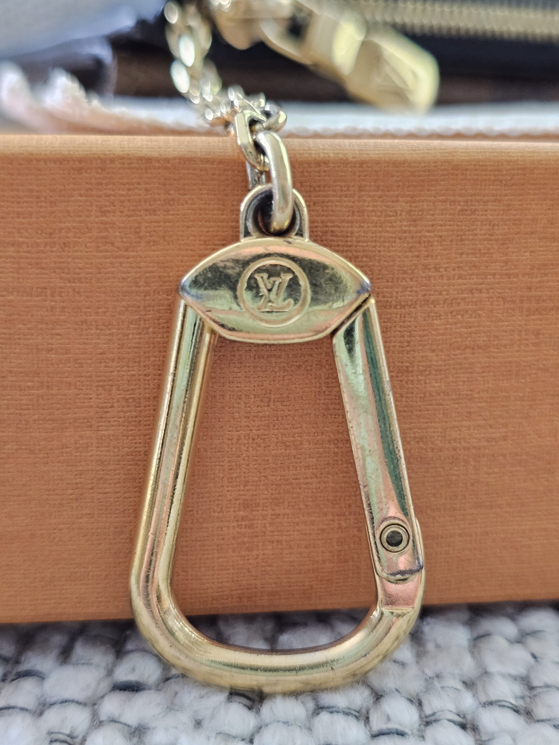 Gold-tone Louis Vuitton signature hook on the chain of the Recto Verso card holder