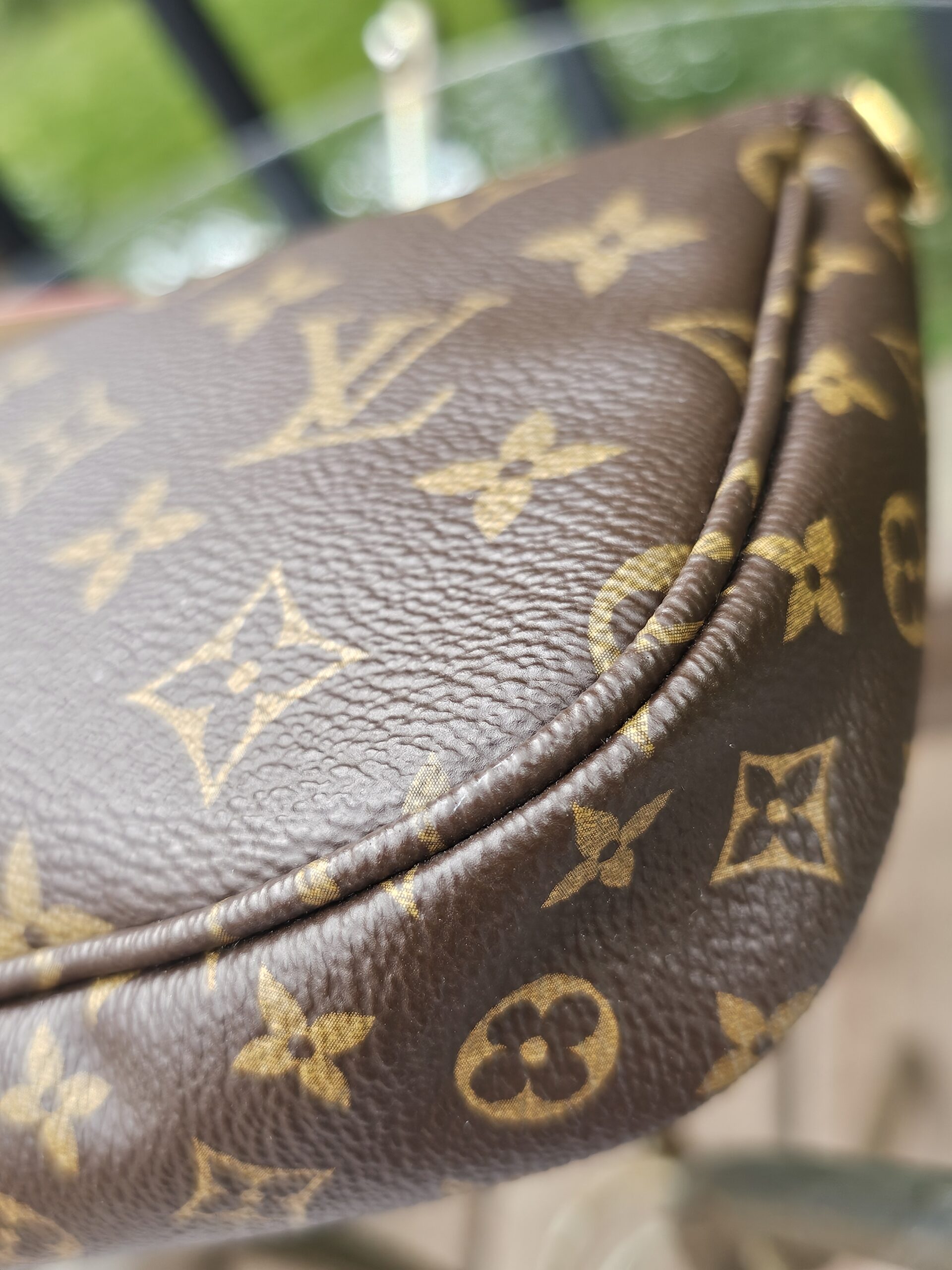 Corner of the Monogram large pochette showing clean piping and canvas