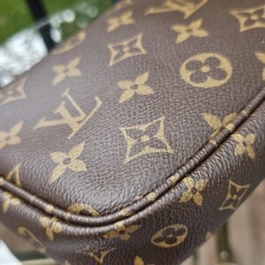 Rounded corner of the Monogram large pochette with the piping in view