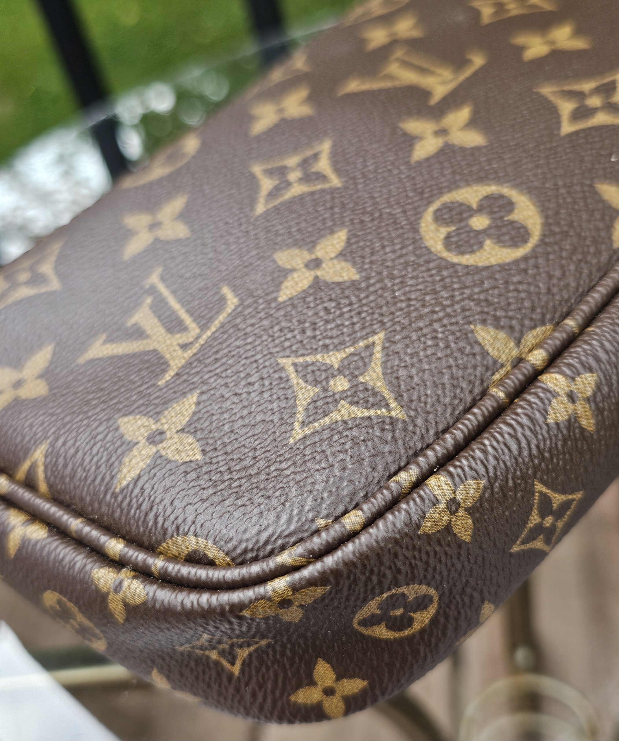 Rounded corner of the Monogram large pochette with the piping in view