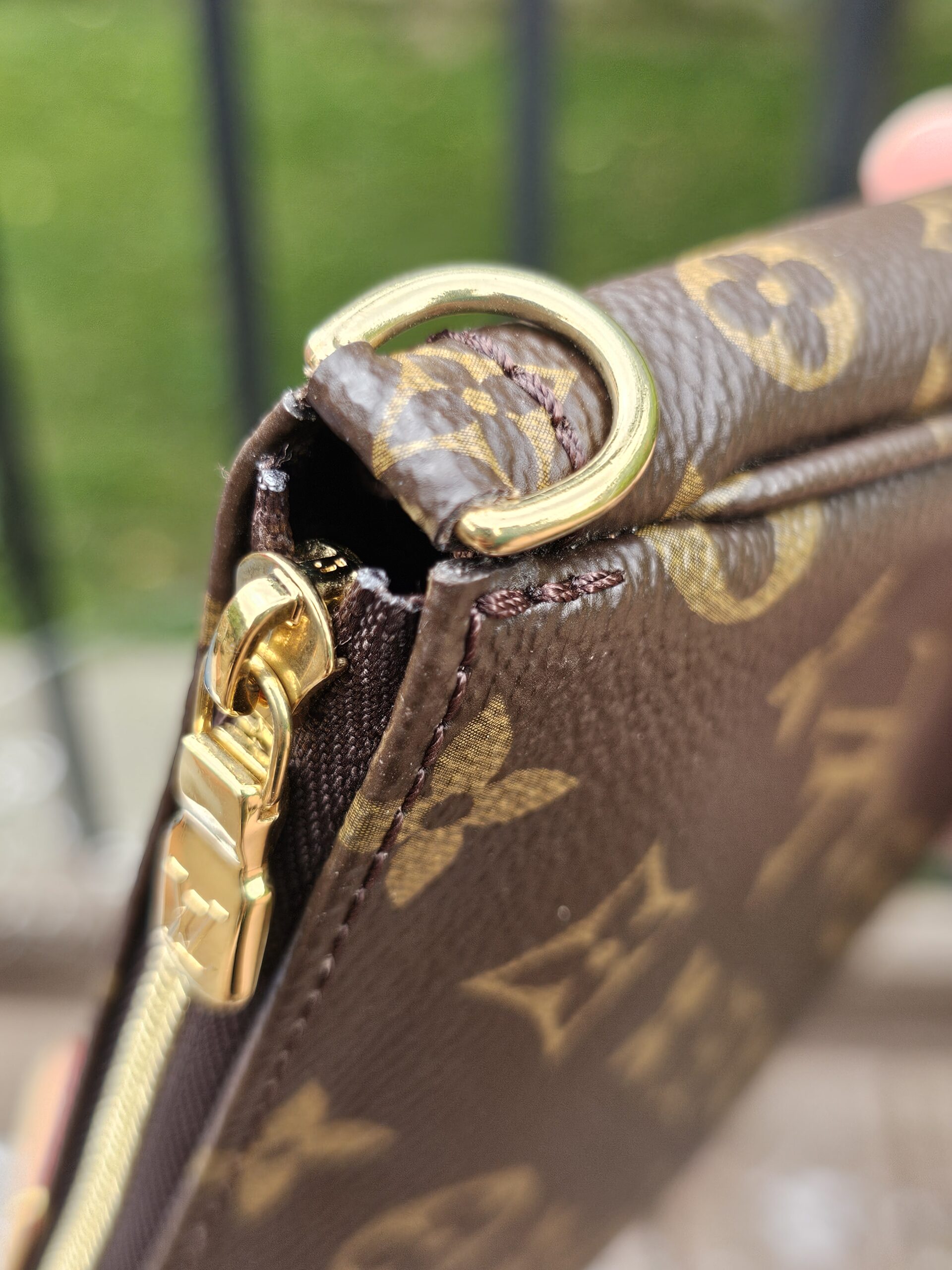 Gold-tone D-ring and zip hardware on the Monogram large pochette