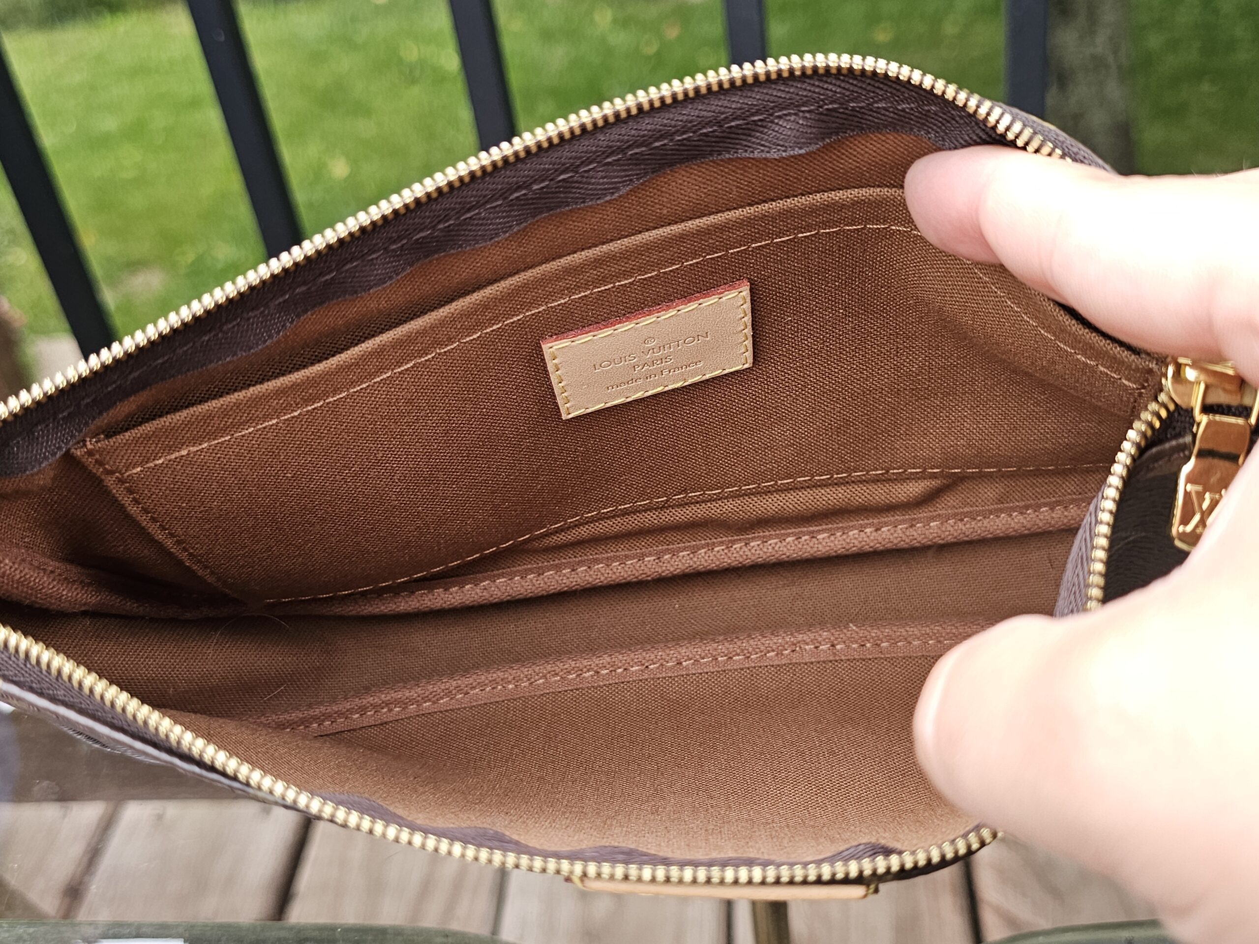 Monogram large pochette held open to show the clean brown interior