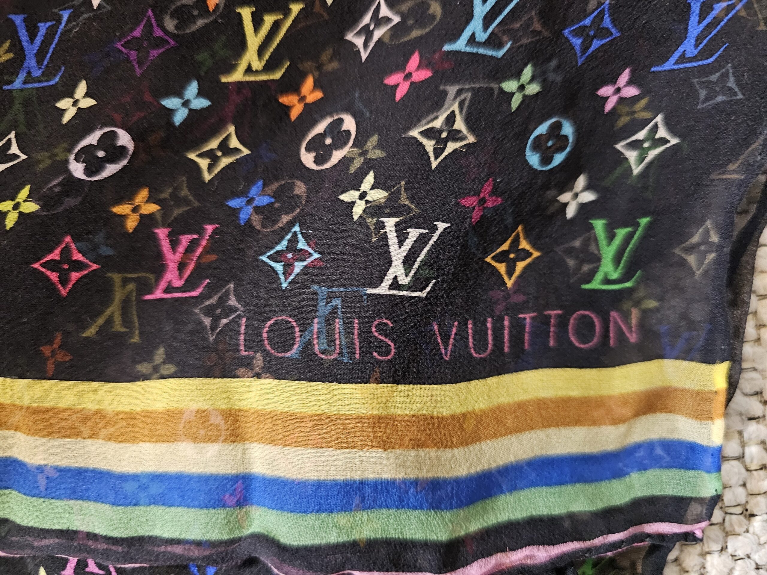 LOUIS VUITTON lettering above the multicolor striped border of the crepe scarf