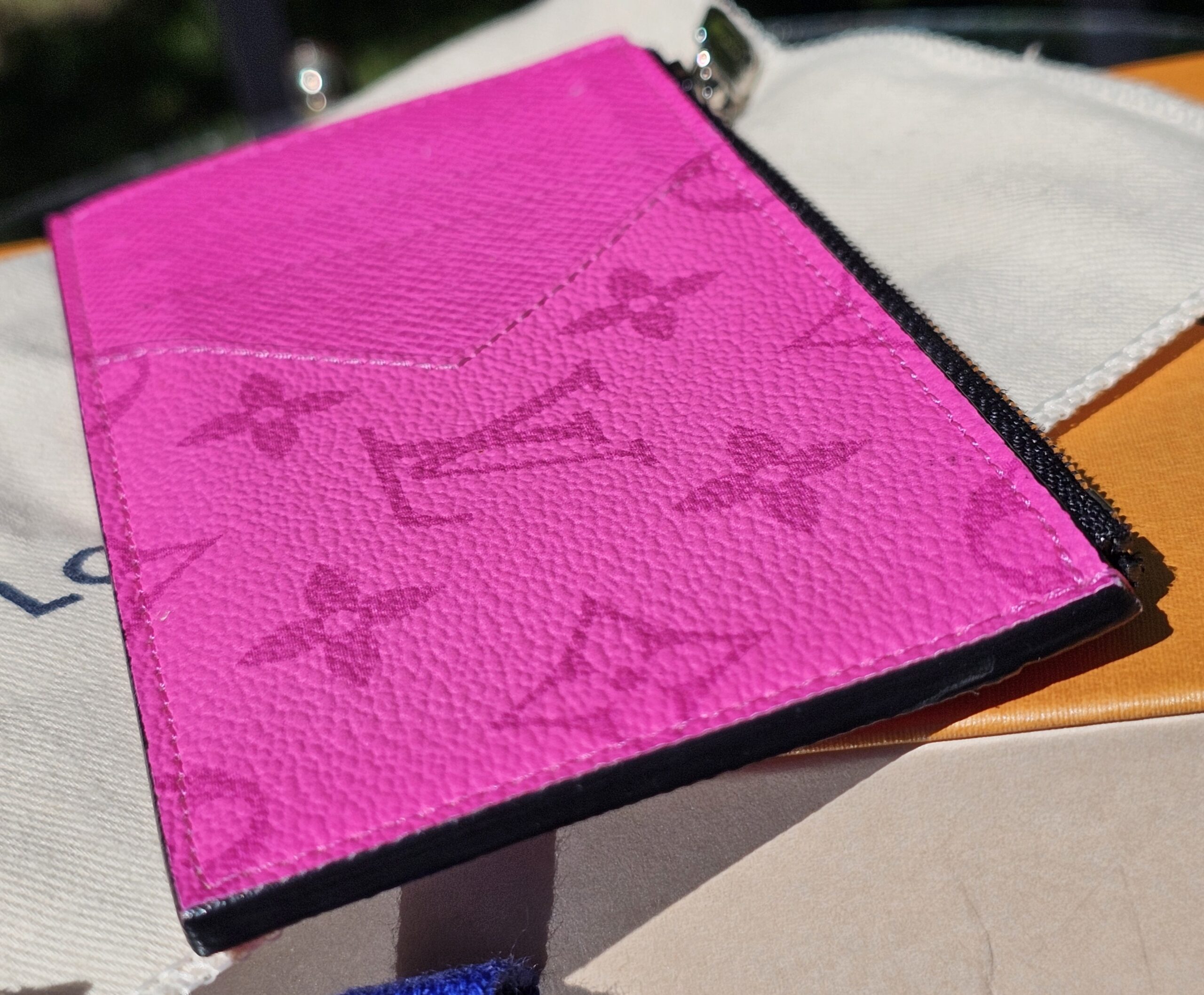 Front of the fuchsia Taigarama card holder resting on its dust bag