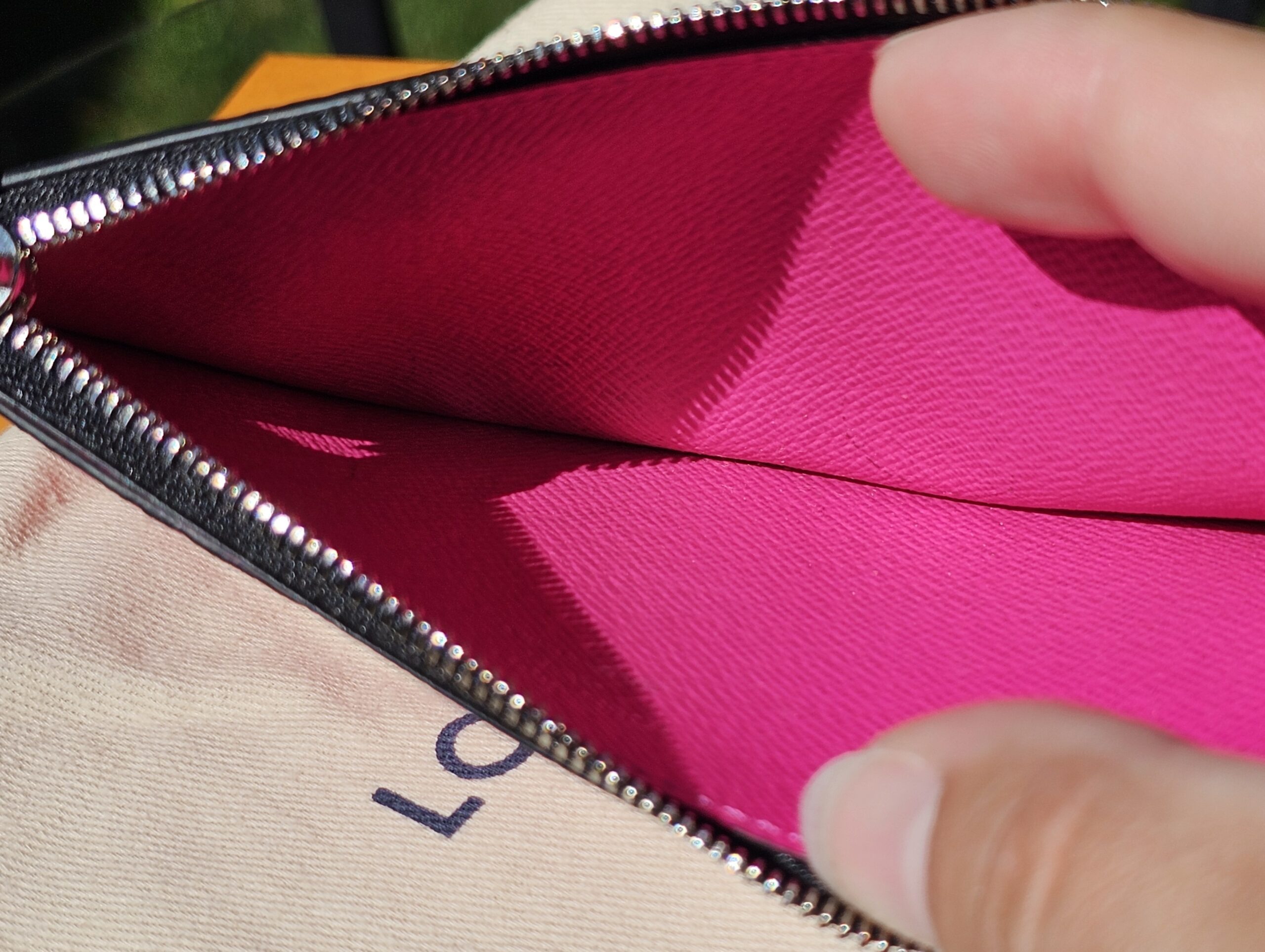Zip coin compartment of the fuchsia card holder held open