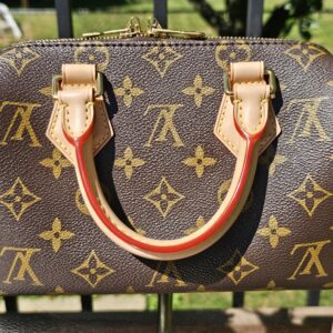 Side of the Speedy Bandouliere 20 with the vachetta handle and red trim