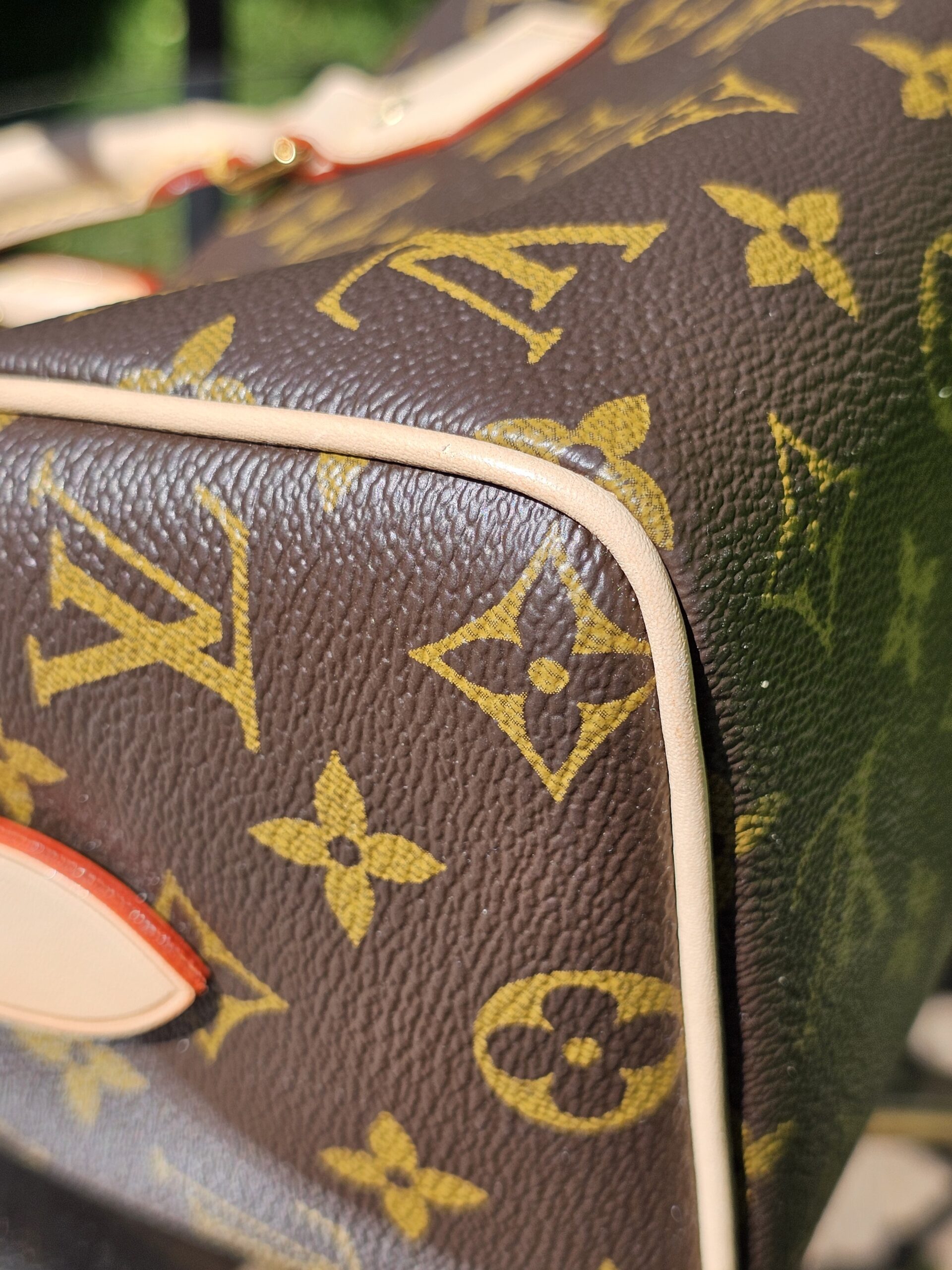 Lower corner and red piping of the Monogram Speedy