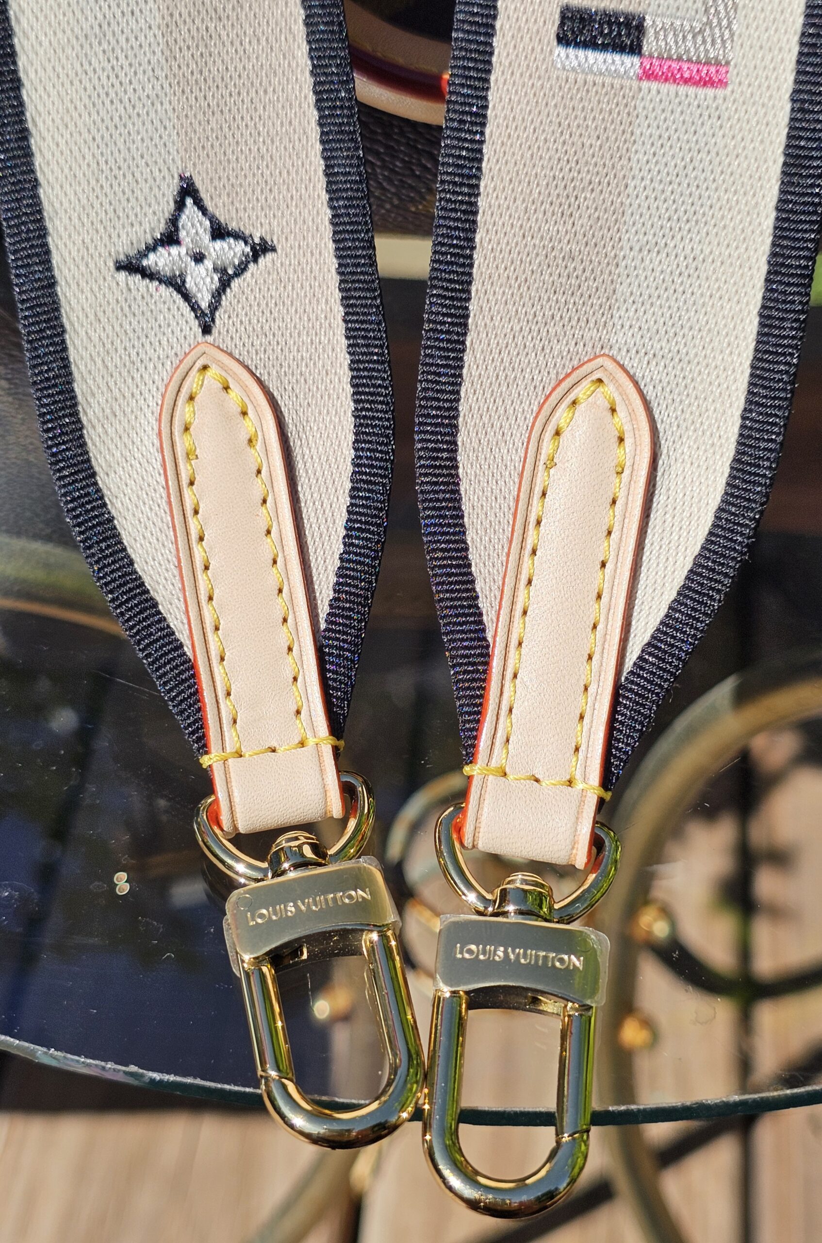 Vachetta tabs and gold-tone snap hooks on the printed strap