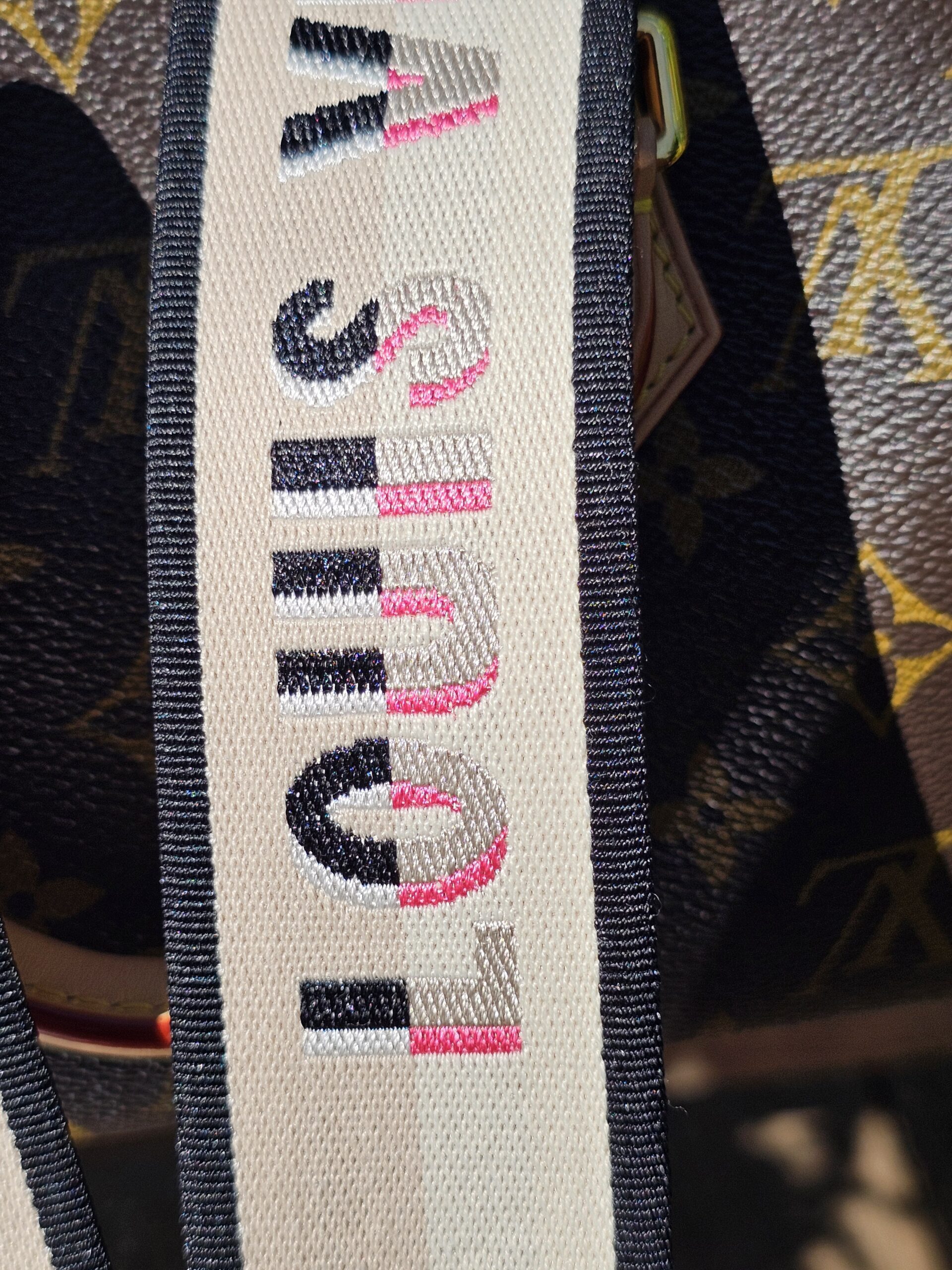 LOUIS VUITTON printed in pink on the cream shoulder strap