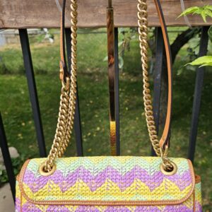 GG Marmont raffia bag hanging by its chain and leather strap