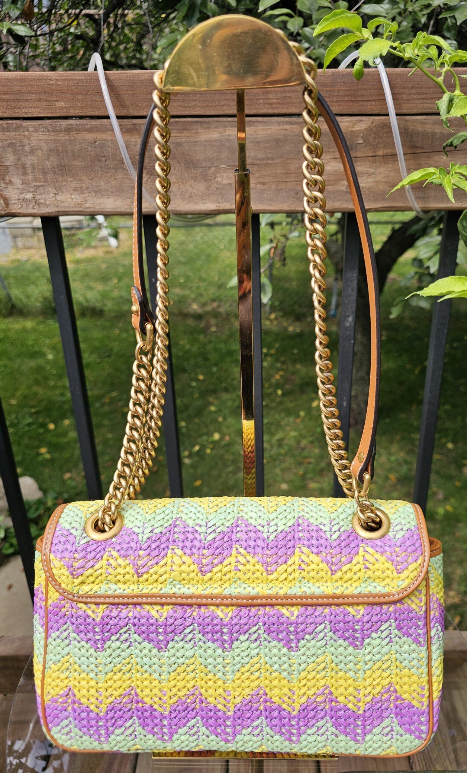 GG Marmont raffia bag hanging by its chain and leather strap