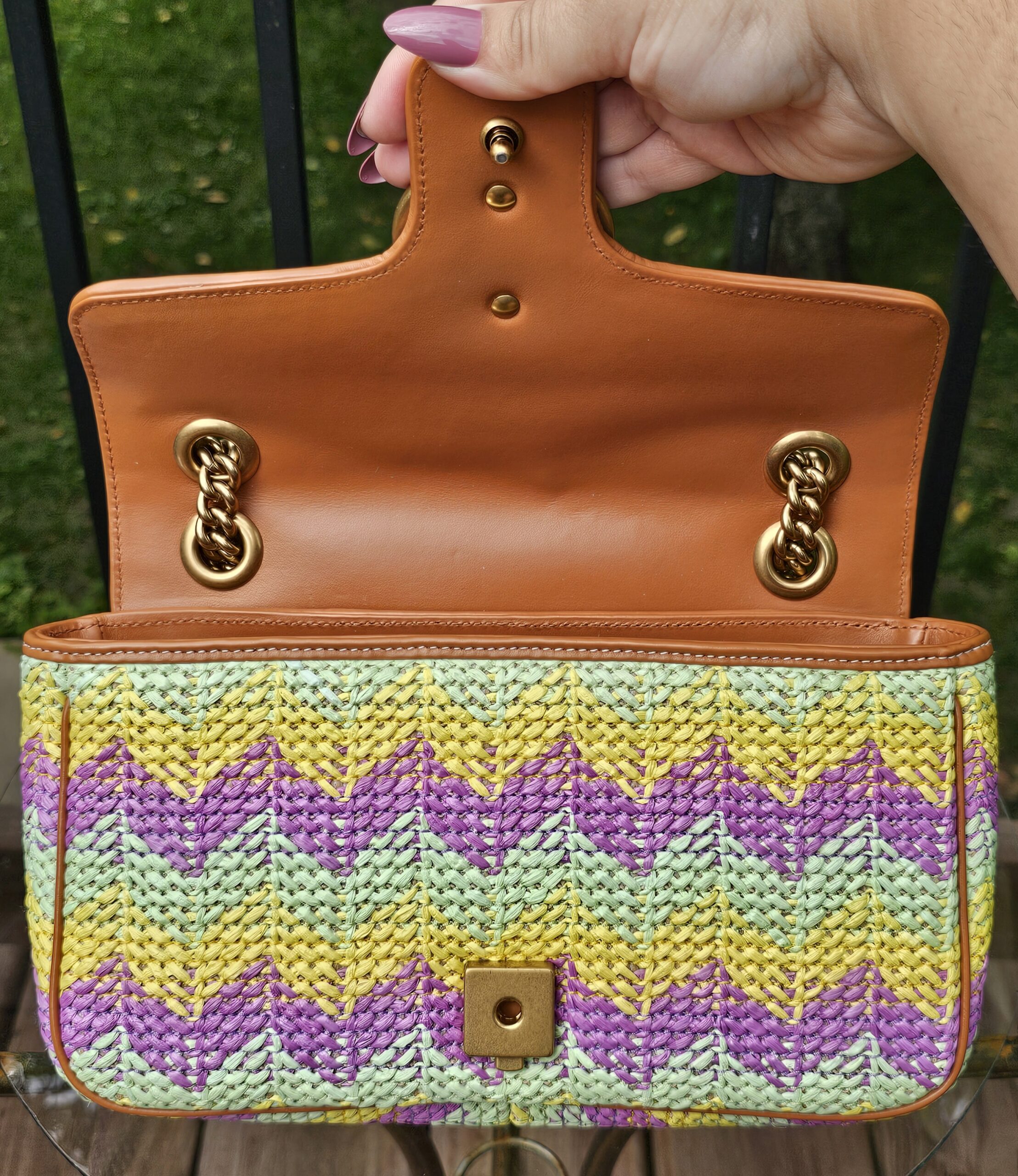 Flap lifted to show the tan leather underside and chain attachment