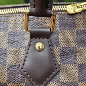 Handle attachment tab and gold-tone stud on the Damier Ebene Speedy