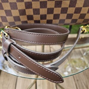 Leather strap coiled beside the Damier Ebene canvas